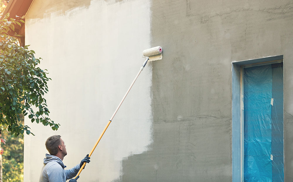 Hombre pintando una pared gris con un rodillo