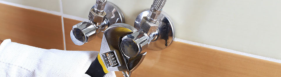 Usuario ajustando mangueras de mezcladora a llaves de paso con una llave