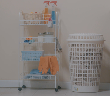 Lavandería con lavadora y secadora de carga frontal y estante con ropa colgada, plancha, toallas y productos de limpieza ordenados