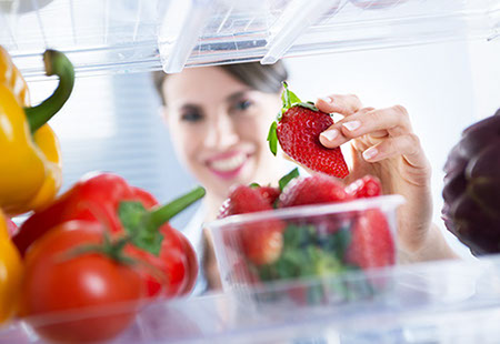 Usuaria colocando fresas en un recipiente dentro del refrigerador